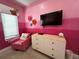 Pink bedroom with TV, comfy chair, and large dresser at 331 Muirfield Loop, Reunion, FL 34747
