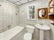 Bathroom with pedestal sink and tiled bathtub at 303 Carleton St, Lakeland, FL 33803