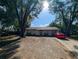 Ranch style home with a red car parked in the driveway, surrounded by large trees at 1301 Redwood Ct, Tavares, FL 32778