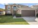 Two-story house with a brown garage door and arched entryway, well-maintained lawn at 6844 Pomeroy Cir, Orlando, FL 32810