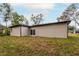 Tan house exterior with a sliding glass door and grassy yard at 405 N Mcdonald Ave, Deland, FL 32724