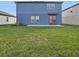 View of a two-story home's backyard, featuring a small patio and a grassy lawn at 1426 Arbor Hill Dr, Deltona, FL 32725