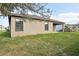 Tan house exterior with dark windows, covered patio, and grassy backyard at 279 Fig Ct, Poinciana, FL 34759