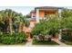 Two-story building with peach-colored facade, lush landscaping, and palm trees at 101 New Providence # 9101, Davenport, FL 33897