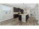 Open kitchen features island with seating, dark cabinetry, and wood-look flooring at 5443 Carrara Ct, St Cloud, FL 34771