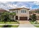 Two-story home with a brown door and three-car garage at 1110 Watson Ct, Reunion, FL 34747