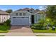 House exterior with gray garage and light-blue walls. Landscaped yard and brick driveway at 2160 Antilles Club Dr, Kissimmee, FL 34747