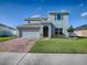 Two-story house with a gray exterior, brick driveway, and landscaped lawn at 911 Avenal, Davenport, FL 33837