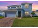 Two-story house with a gray exterior, brick driveway, and landscaped lawn at 911 Avenal, Davenport, FL 33837