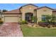 Tan one-story house with brown roof, brick paver driveway, and landscaped yard at 941 Rimini Dr, St Cloud, FL 34771