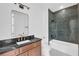 Bathroom with dark tile shower, white tub, and wood vanity at 155 Pearl St, Auburndale, FL 33823