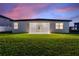 White house with covered patio and grassy lawn at dusk at 1877 Snapper Dr, Kissimmee, FL 34759