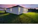 White house with backyard and grassy lawn at dusk at 1877 Snapper Dr, Kissimmee, FL 34759