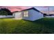 White house with backyard and grassy lawn at dusk at 1877 Snapper Dr, Kissimmee, FL 34759