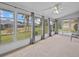 Spacious screened porch with backyard views and gray curtains at 21523 Queen Anne Ct, Leesburg, FL 34748