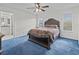 Spacious bedroom with blue carpet, ceiling fan, and ensuite bathroom access at 21523 Queen Anne Ct, Leesburg, FL 34748