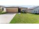 Tan one-story house with a two-car garage and green lawn at 928 Orchid Grove Blvd, Davenport, FL 33837