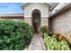 Brick entryway with arched detail, red door, and lush landscaping at 2626 Raccoon Run Ln, Orlando, FL 32837