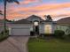 One-story home with a two-car garage and landscaped yard at sunset at 235 Royal Palm Dr, Davenport, FL 33837