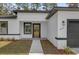 Modern house exterior with gray and white color scheme and a wood front door at 15123 Sw 61St Court Rd, Ocala, FL 34473