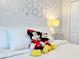 Charming bedroom with Mickey and Minnie Mouse plushies, white bedding, and a decorative wallpaper at 3053 Gatsby St, Kissimmee, FL 34746