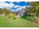 Large backyard with grassy area, trees, and screened pool at 709 Lake Emerald Ave, Orange City, FL 32763