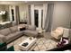 Open living room with gray sectional sofa, geometric rug, and large windows at 14739 Glade Hill Park Way, Winter Garden, FL 34787