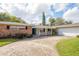 Brick ranch house with a two-car garage, landscaping, and a long driveway at 2518 Sweetwater Trl, Winter Park, FL 32789