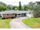 Brick home with a circular driveway, landscaped lawn, and attached garage at 2518 Sweetwater Trl, Winter Park, FL 32789