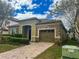 One-story house with stone and green siding, a two-car garage, and a landscaped yard at 9030 Shadow Mountain St, Davenport, FL 33896