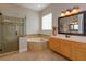 Primary bathroom with corner tub, glass shower, and wood cabinets at 6893 Hidden Glade Pl, Sanford, FL 32771