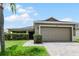 Tan single story house with a two car garage and lush landscaping at 806 Knightsbridge Cir, Davenport, FL 33896