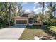 Tan house with stone accents and a screened porch, two car garage, and landscaped yard at 1989 Marsh Hen Vlg, Deland, FL 32720