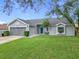 Gray house with a blue door, two-car garage, and well-manicured lawn at 7471 Crooked Lake Cir, Orlando, FL 32818
