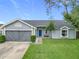 Gray house with a blue door, two-car garage, and a well-maintained lawn at 7471 Crooked Lake Cir, Orlando, FL 32818