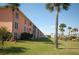 Landscaped lawn and palm trees in front of the light peach condominium building at 721 S Beach St # 217A, Daytona Beach, FL 32114
