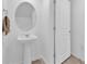 Small bathroom with pedestal sink and round mirror at 1174 Seaside Mist Trl, Kissimmee, FL 34747