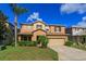 Two story house with tan exterior, landscaping, and a two-car garage at 315 Aldridge Ln, Davenport, FL 33897