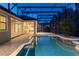 Night view of a screened pool and patio area with outdoor kitchen at 8681 Crested Eagle Pl, Sanford, FL 32771