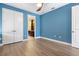 Bedroom with blue walls, wood-look flooring, and double doors to closet at 8681 Crested Eagle Pl, Sanford, FL 32771