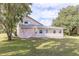 Rear view of a light pink house with detached structure, surrounded by green lawn at 23035 Fort Christmas Rd, Christmas, FL 32709