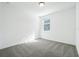 Simple bedroom with grey carpet, window with blinds, and white walls at 28054 Poppy Ct, Leesburg, FL 34748
