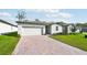 One-story home with white siding, white garage door, and a brick paver driveway at 28054 Poppy Ct, Leesburg, FL 34748