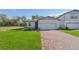 One-story home with gray siding, brick paver driveway, and landscaped lawn at 28066 Poppy Ct, Leesburg, FL 34748