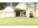 Tan one-story house with three-car garage and manicured lawn at 4420 Heritage Trl, Leesburg, FL 34748
