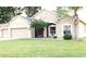 Tan one-story house with three-car garage and manicured lawn at 4420 Heritage Trl, Leesburg, FL 34748