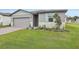 Gray house with light blue shutters, landscaping, and a brick driveway at 4751 Jasmine Cir, Leesburg, FL 34748