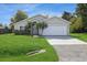 Tan house with white garage door, landscaping, and a spacious lawn at 8518 Rainbow Ave, Orlando, FL 32825