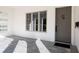 Inviting front porch with light gray tile flooring, and a modern taupe front door at 1781 Goodrich Ave, Winter Park, FL 32789