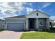 Gray house with white accents, stone facade, and a two-car garage at 6817 Serpent Hawk Lane St, Howey In The Hills, FL 34737